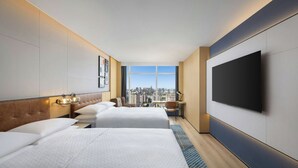 A hotel room with two beds, a large TV, a desk with a chair, and a city view. - Four Points By Sheraton Beijing Sanlitun Workers Stadium (Beijing)