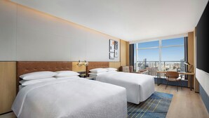 A hotel room with two beds, a desk, and a view of the city. - Four Points By Sheraton Beijing Sanlitun Workers Stadium (Beijing)