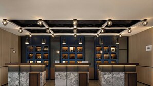 A reception area with marble counters, blue shelving with items, and pendant lighting. - Four Points By Sheraton Beijing Sanlitun Workers Stadium (Beijing)