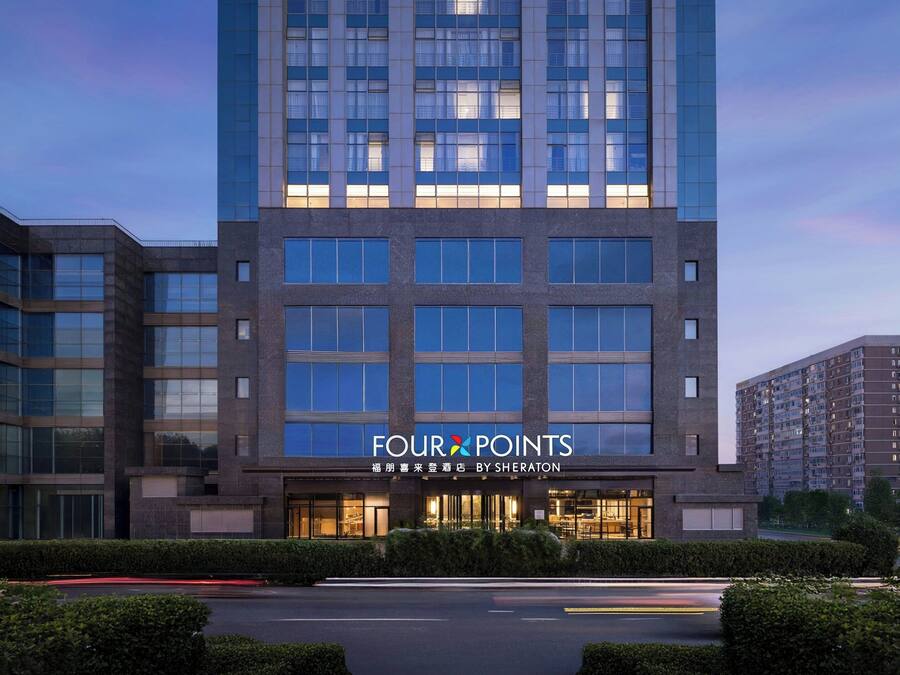 A modern hotel building with a prominent 'Four Points' sign, featuring a clean, rectangular facade with large windows and a well-lit entrance.