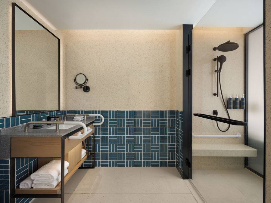 A modern bathroom with a freestanding sink, a mirror, a towel rack, a shower enclosure, and a tiled backsplash.