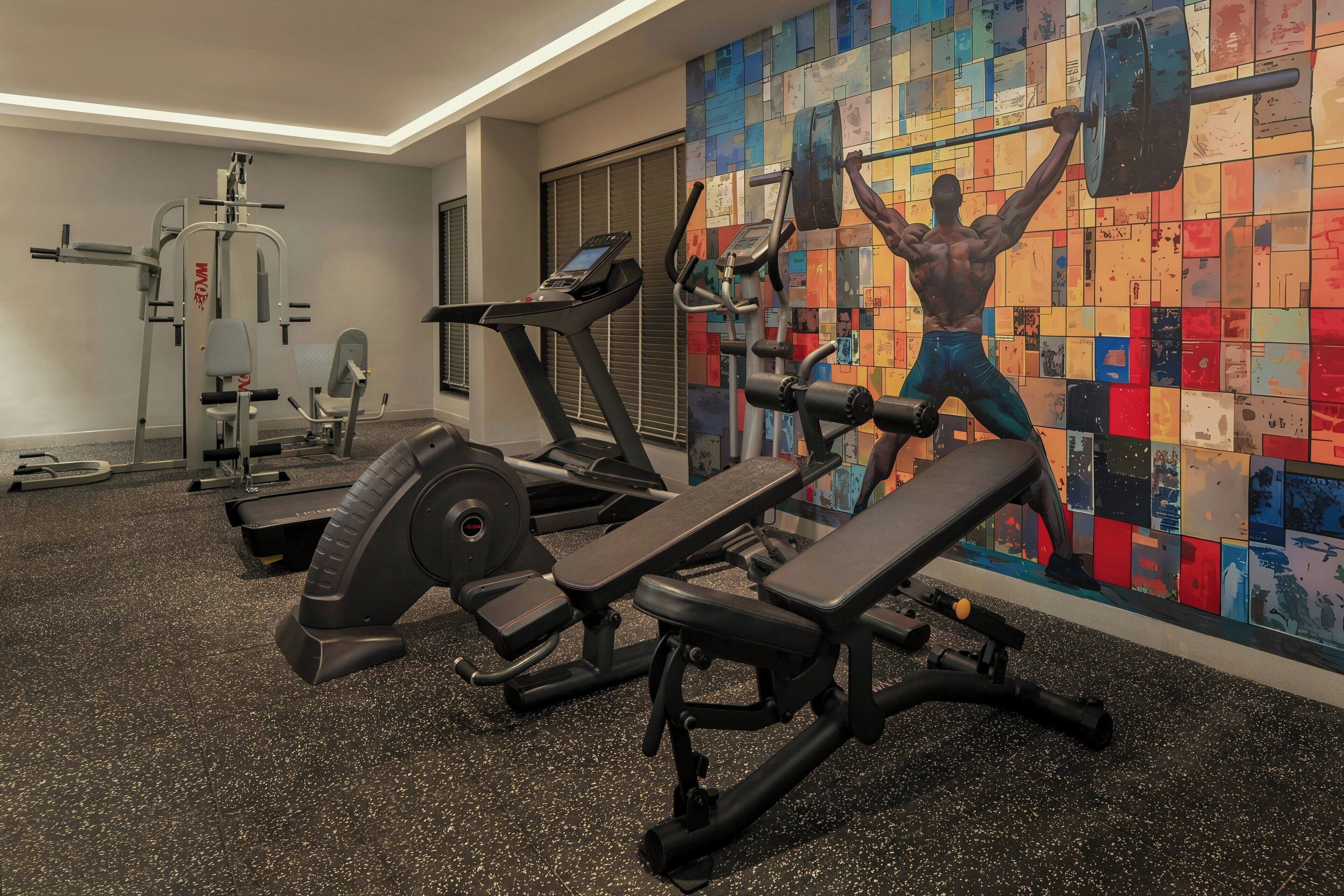 A gym with various exercise equipment, including a bench press, a treadmill, and weight machines.