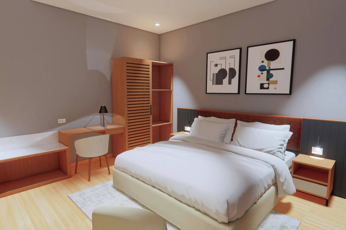 A modern hotel room with a large bed, a desk, a chair, and a wardrobe. There are two framed artworks on the wall.