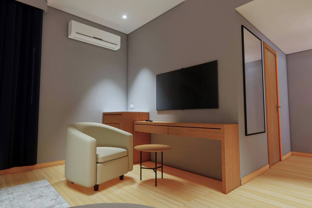 A modern living room with a sofa, a small table, a TV mounted on the wall, and an air conditioning unit.