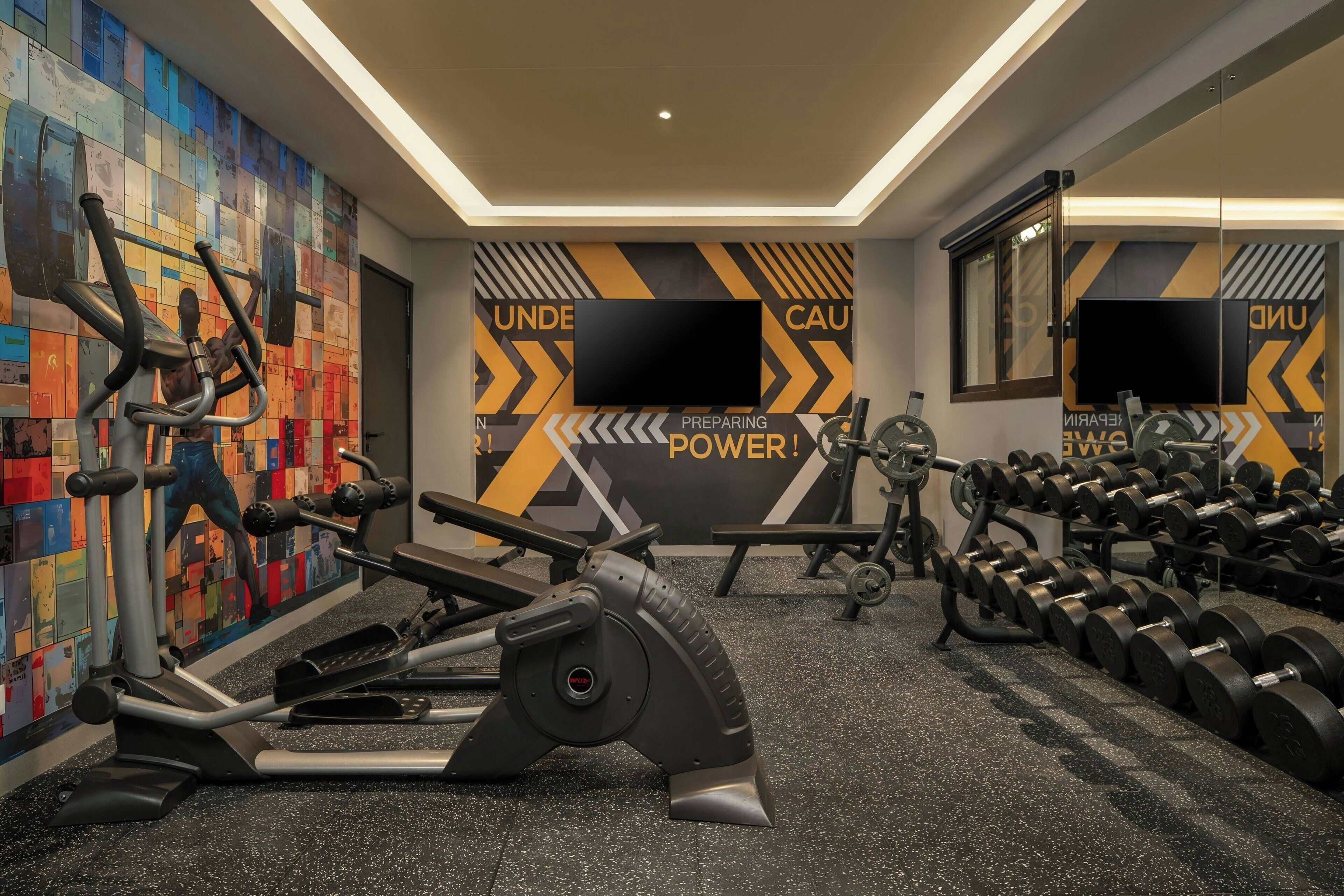 A gym with exercise equipment, a motivational wall, and a mirror.