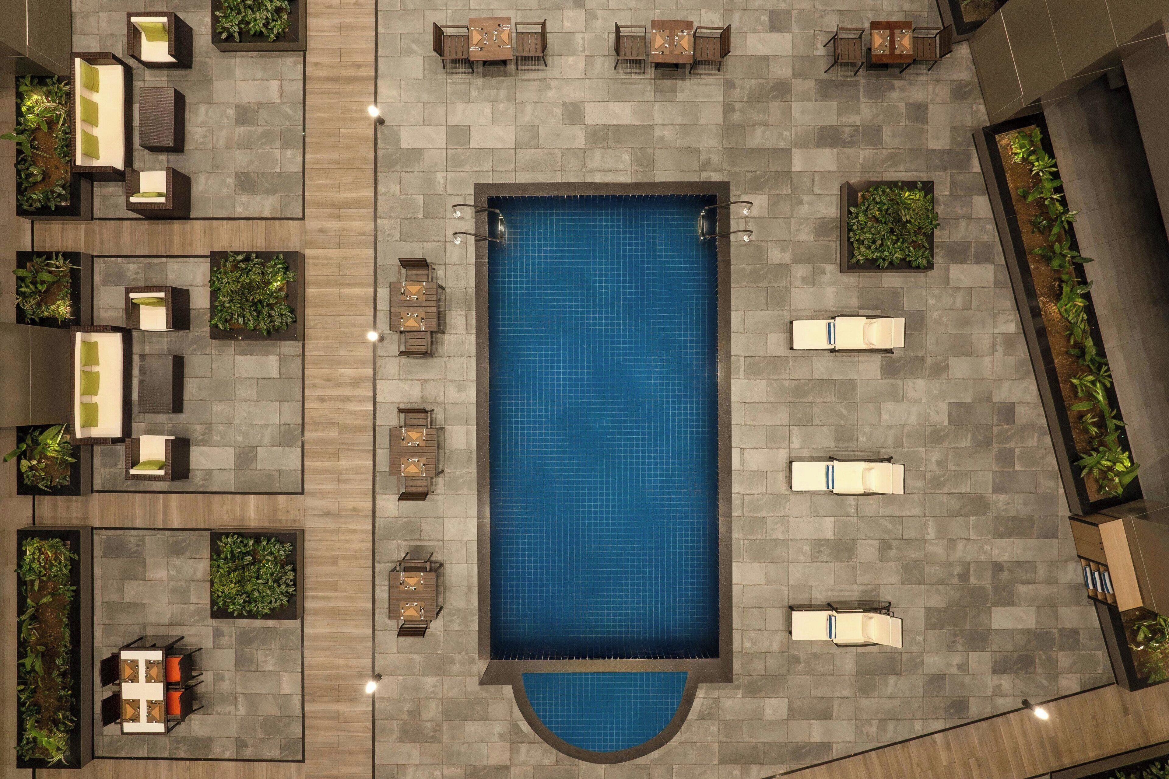 An aerial view of a rooftop pool area with multiple seating areas and planters.