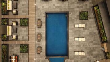 An aerial view of a rooftop pool area with multiple seating areas and planters.