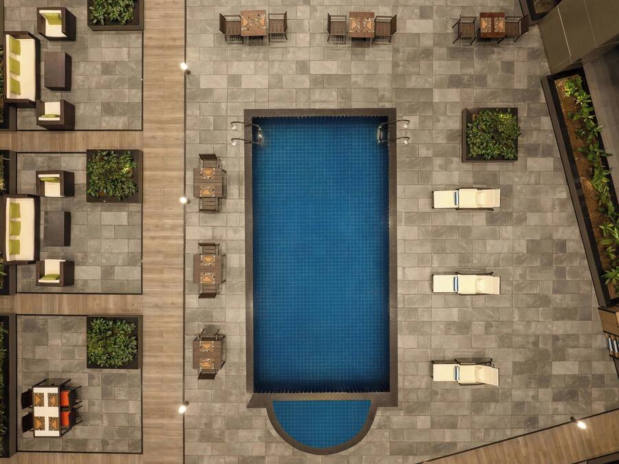 An aerial view of a rooftop pool area with multiple seating areas and planters.