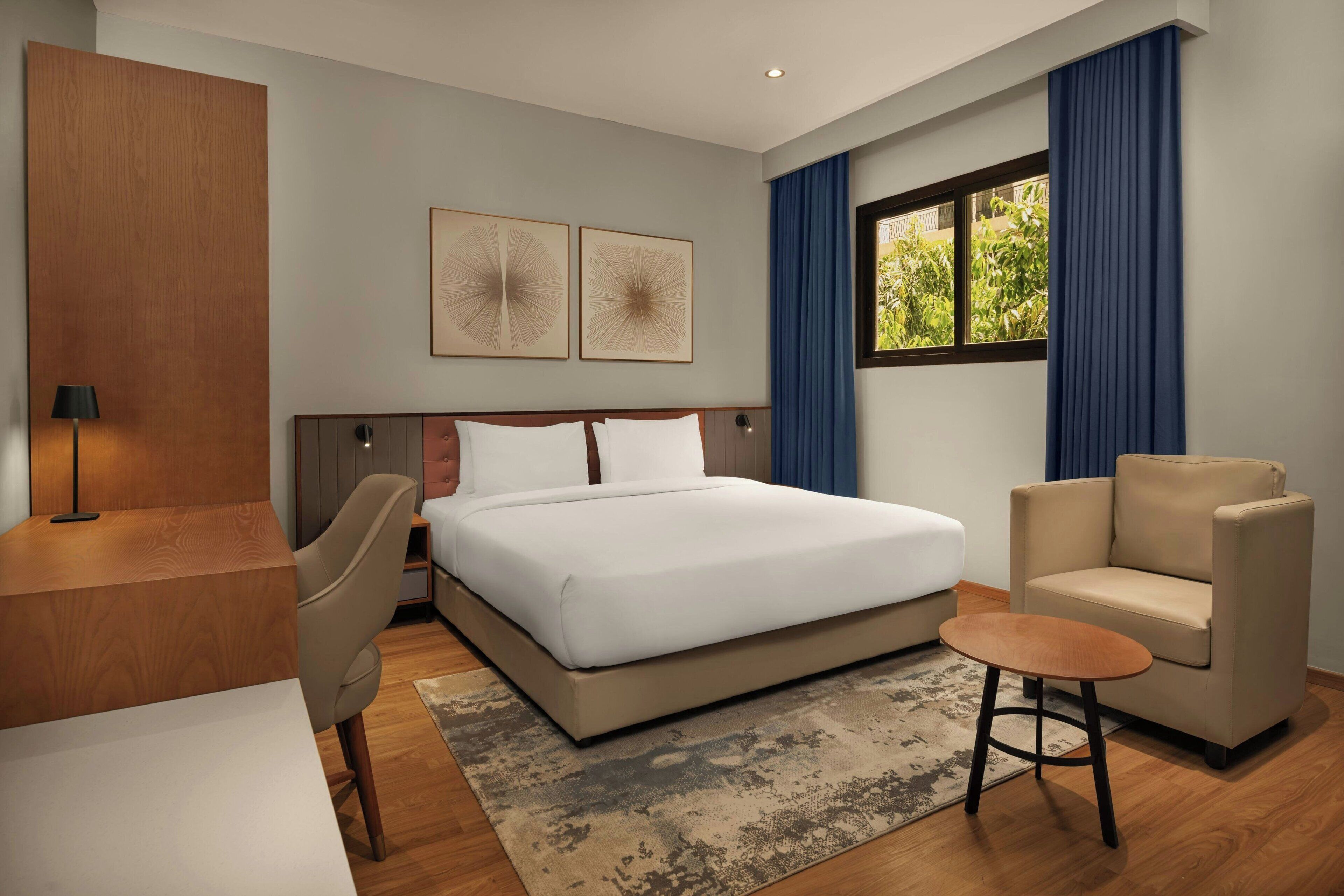 Una habitación de hotel moderna con una cama grande, un escritorio, una silla y un sofá.