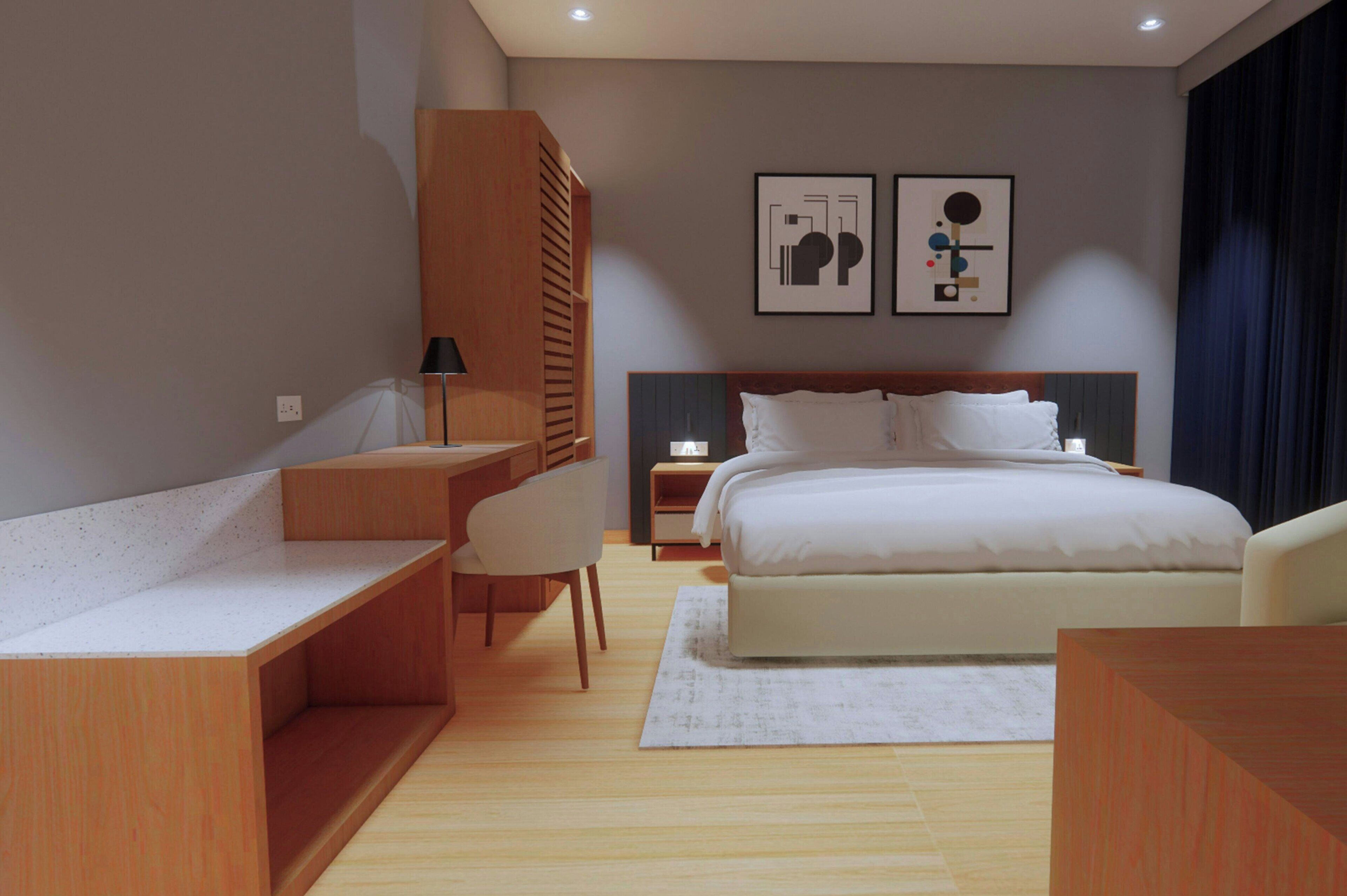 A modern hotel room with a bed, a desk, and a chair. There are two framed pictures on the wall.