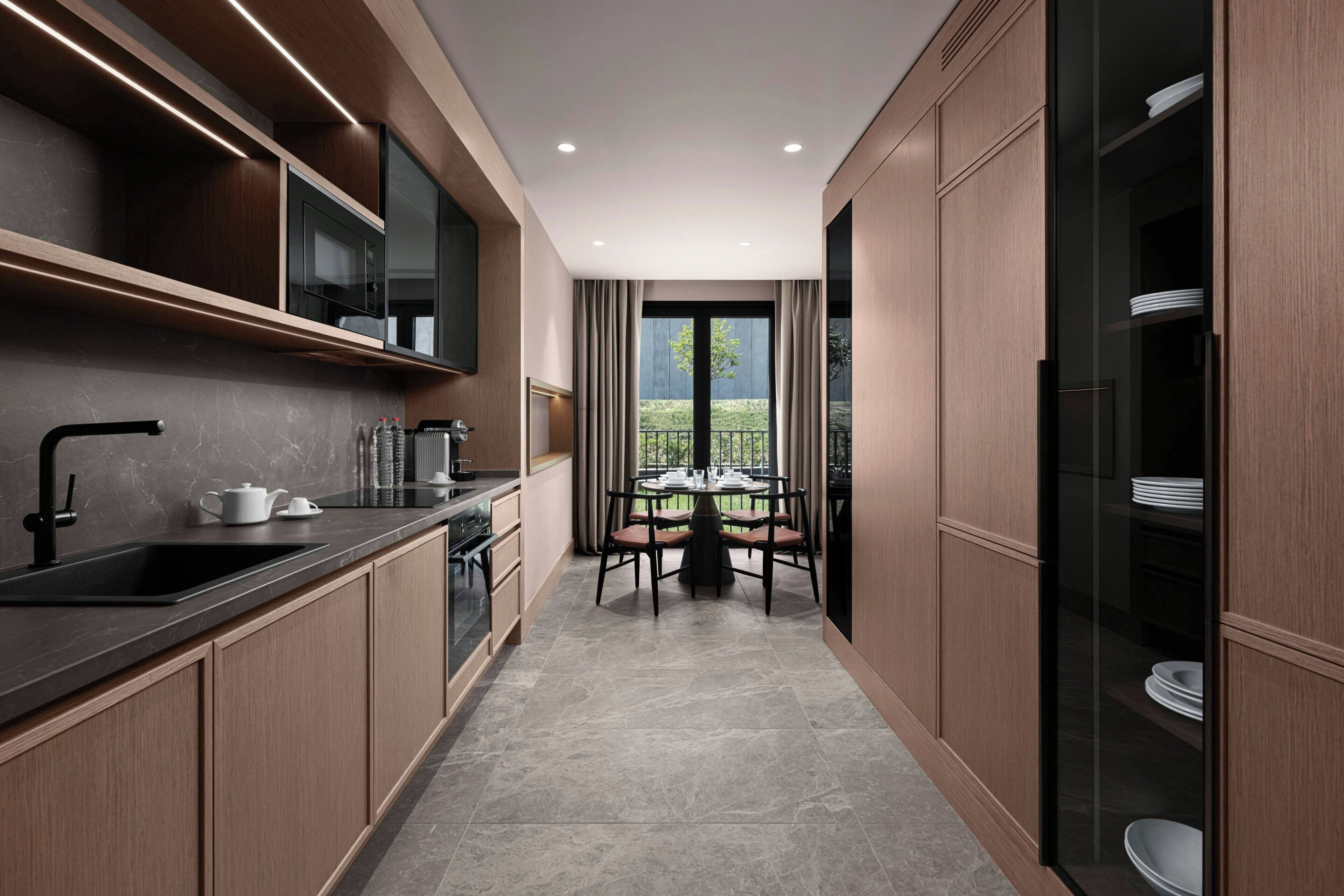 A modern kitchen with a built-in oven, a sink, and a dining area with a table and chairs.