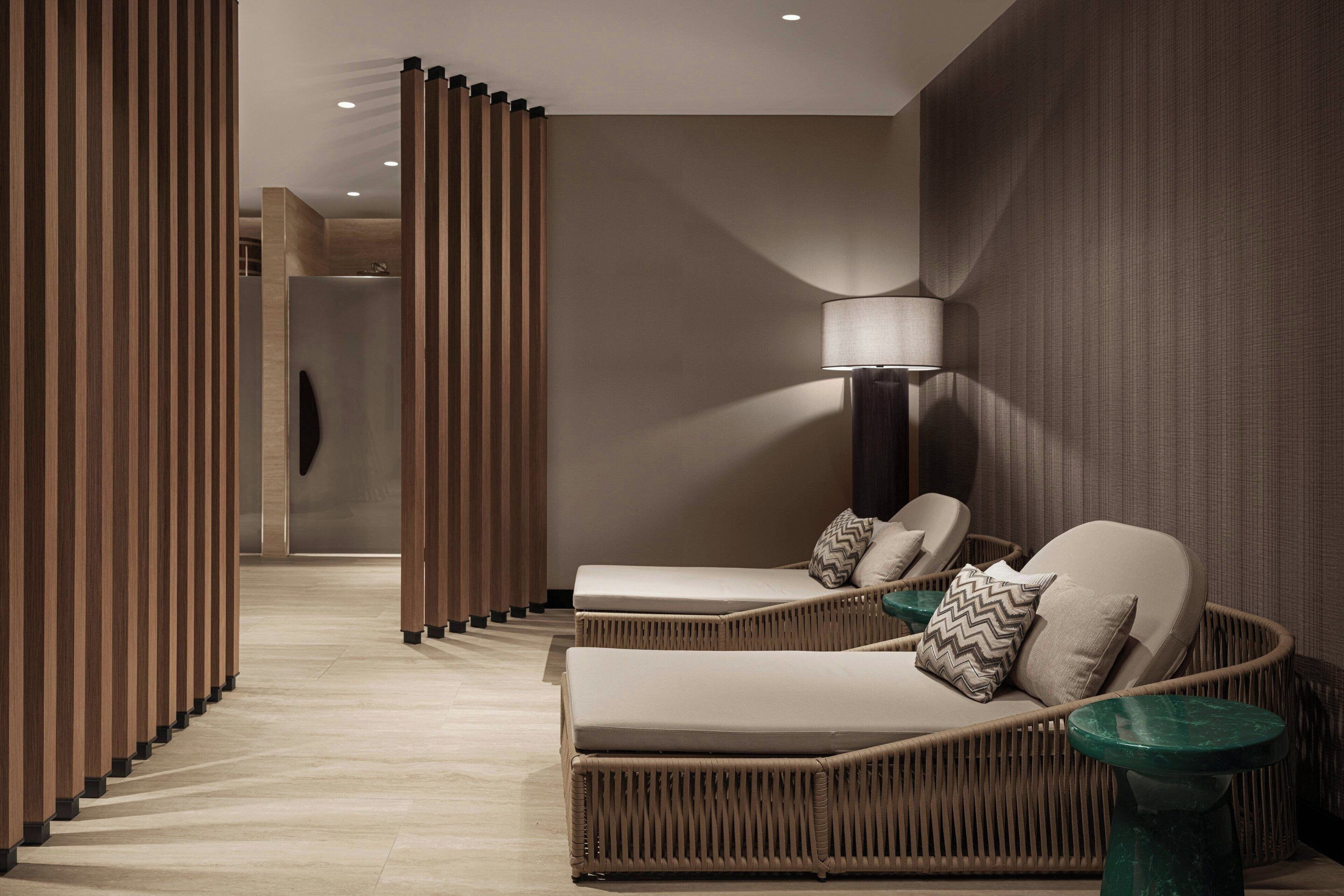 Ein stilvoller Lounge-Bereich mit Rattanmöbeln, einer Stehlampe und einer Holzwand.