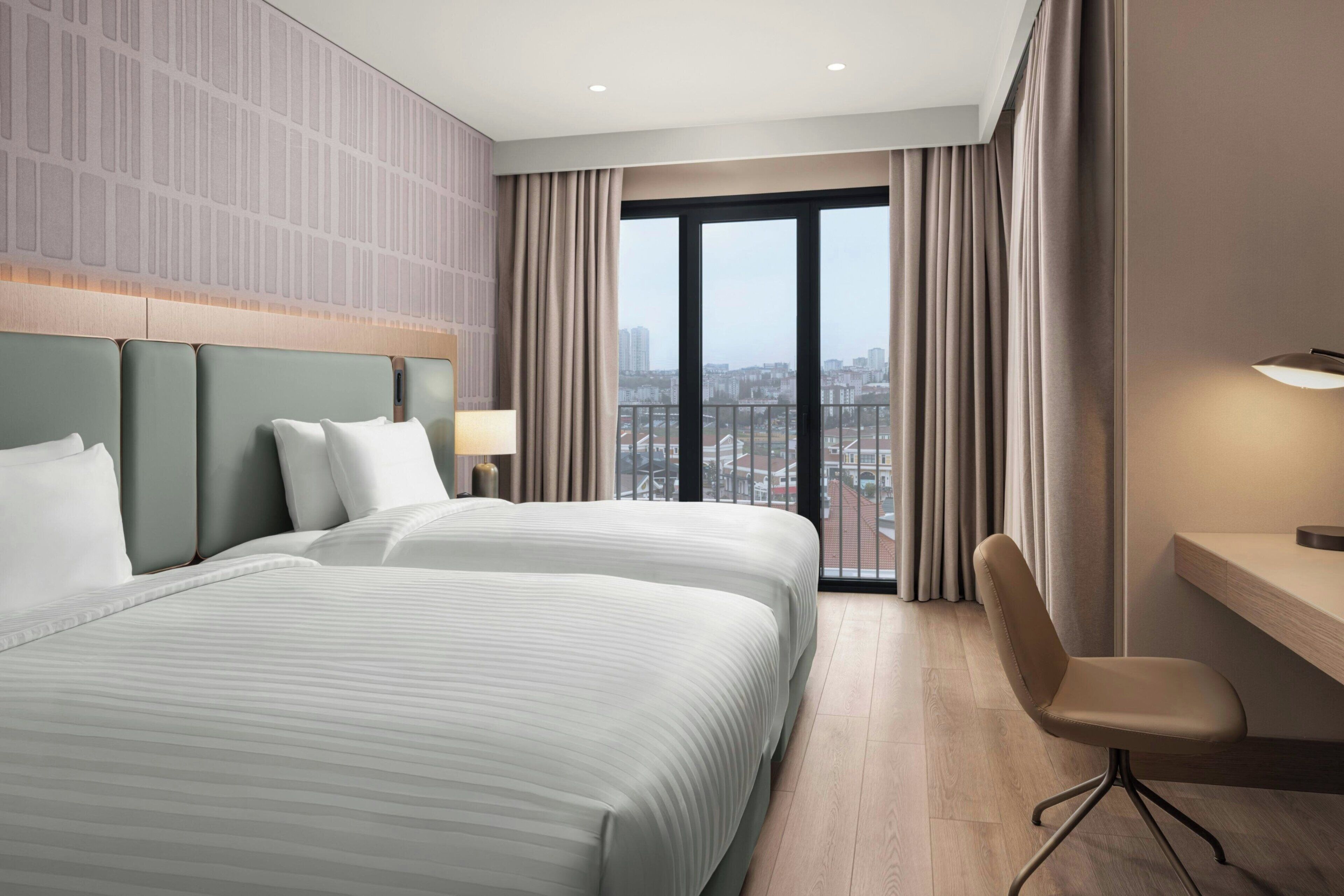 A hotel room with two beds, a desk, and a chair.