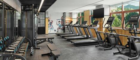 A gym with treadmills, weight machines, and dumbbells.