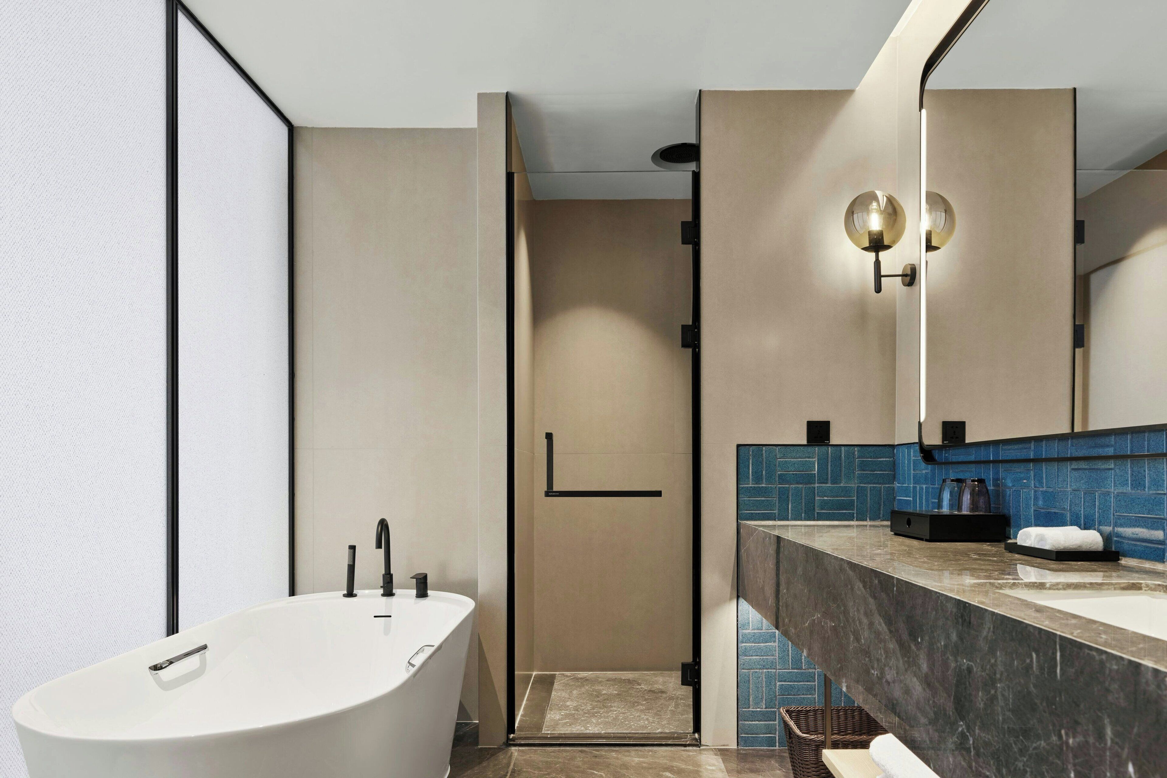 Un baño moderno con una bañera independiente, un espejo grande y una zona de ducha.