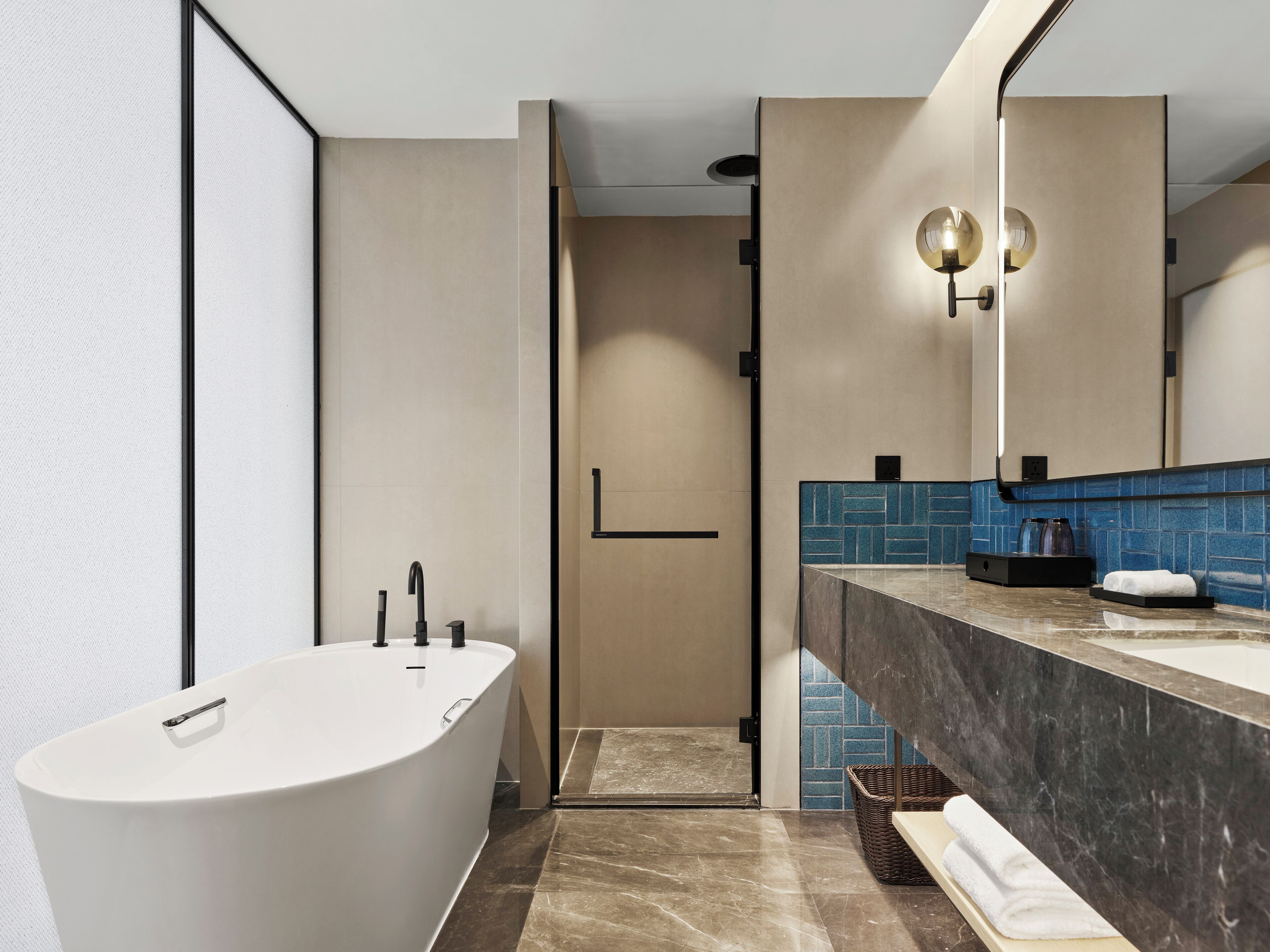 A modern bathroom with a freestanding bathtub, a shower area, and a vanity with a mirror and towel rack.