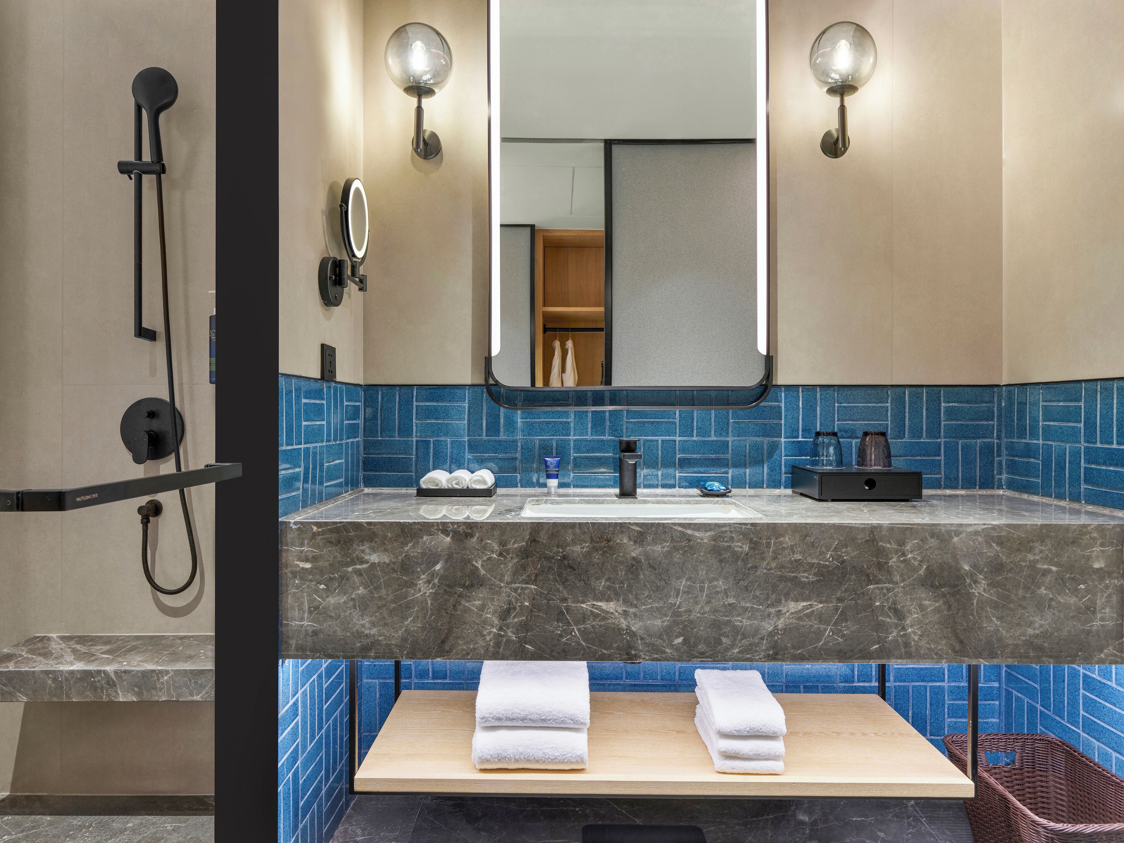 Une salle de bain moderne avec un meuble-lavabo en marbre, un grand miroir et un espace douche.