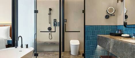A modern bathroom with a freestanding bathtub, a glass-enclosed shower, a vanity with a marble countertop, and a blue-tiled backsplash.