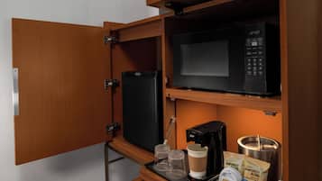 A compact kitchenette with a microwave, coffee maker, and a refrigerator.