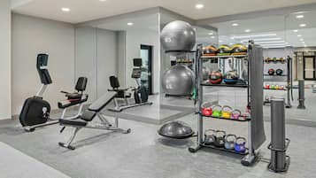 A modern gym with exercise equipment, a weight rack, and a mirrored wall.