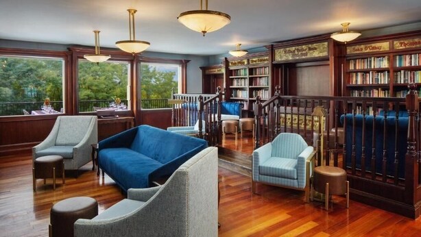 A library with wooden bookshelves, a blue sofa, and a staircase. - Romantic Guestroom Perfect for Couples’ Escape (Galena)