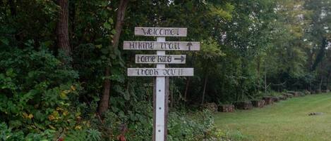 A wooden signpost with directional arrows and text indicating hiking trails and a thank you message.