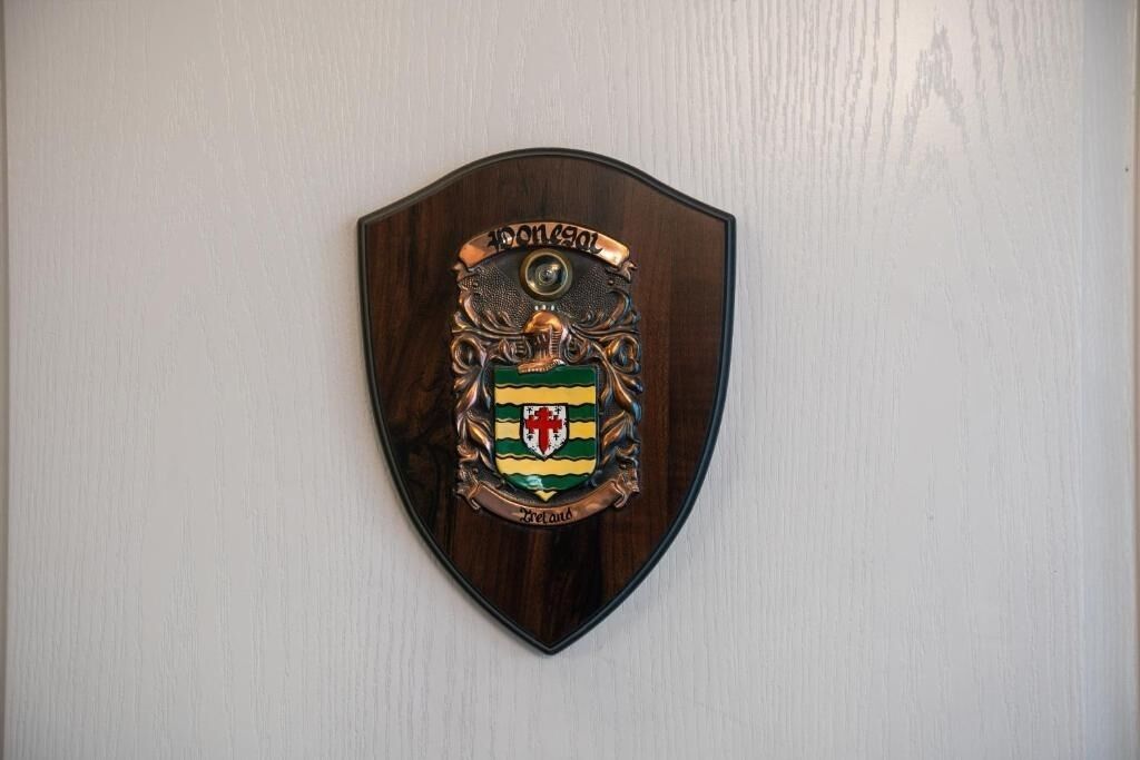 Une plaque en forme de bouclier, ornée d’un blason et du mot « Irlande », est fixée à un mur.