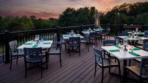 An outdoor dining area with tables and chairs, set against a backdrop of trees and a sunset sky. - Enjoy Irish-Inspired Comfort at Cozy Room in Galena (Galena)