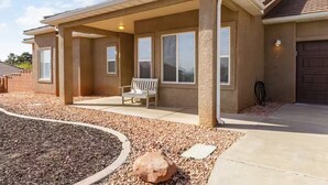 Une maison de plain-pied dotée d’un patio couvert, d’un banc et d’une allée gravillonnée.