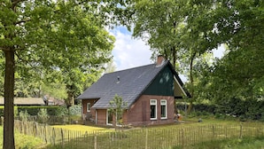 A small brick house with a dark roof, surrounded by a wooden fence and lush greenery. - 3 bedroom beautiful home in Gees (Gees)