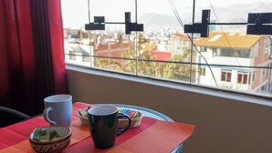A table with a red placemat, a blue mug, a black mug, and a bowl with a patterned design. - Tradición: Studio apartment with a wonderful view, close to San Blas market (Cusco)