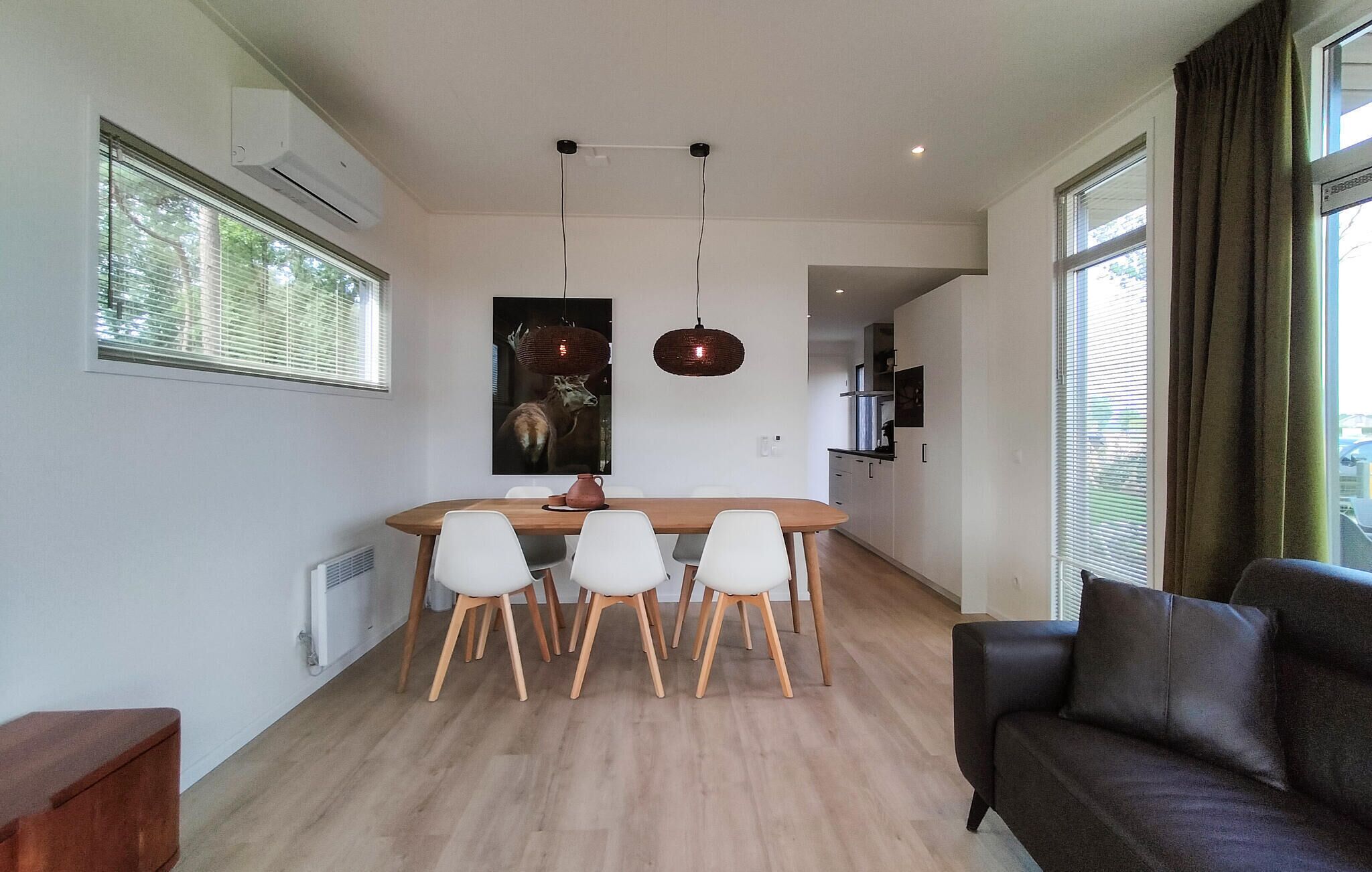 Un espacio habitable moderno con comedor, sofá y cocina al fondo.