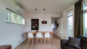A modern living space with a dining area, a sofa, and a kitchen in the background. - 2 bedroom cozy home in Hellendoorn (Hellendoorn)