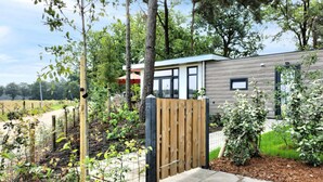 A modern house with a wooden gate, surrounded by a garden with various plants and trees. - 2 bedroom cozy home in Hellendoorn (Hellendoorn)