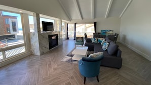 Un salon spacieux doté d’une cheminée, de grandes fenêtres et offrant une vue sur l’extérieur.