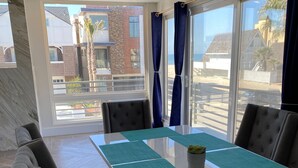 Une salle de réunion moderne, dotée d’une longue table, de sièges confortables et de grandes fenêtres offrant une vue sur la plage et les bâtiments.