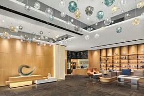 Een moderne lobby met een houten receptiebalie, een gebogen sculptuur en een zithoek met banken en een salontafel.
