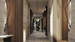 A corridor with wooden walls and a tiled floor, leading to a room with a bed and a window.