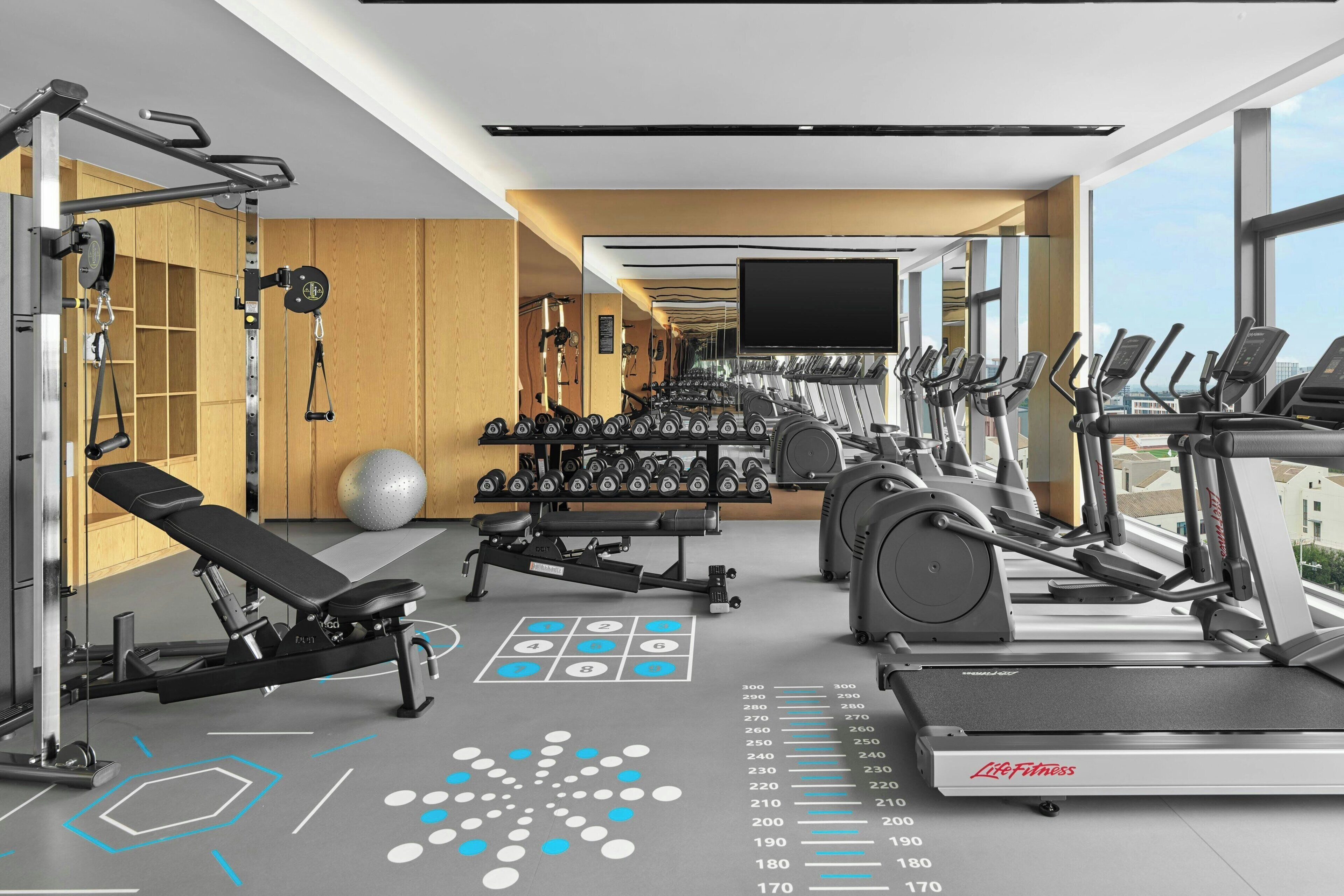 Et moderne fitnesscenter med løbebånd, styrkemaskiner og håndvægte.