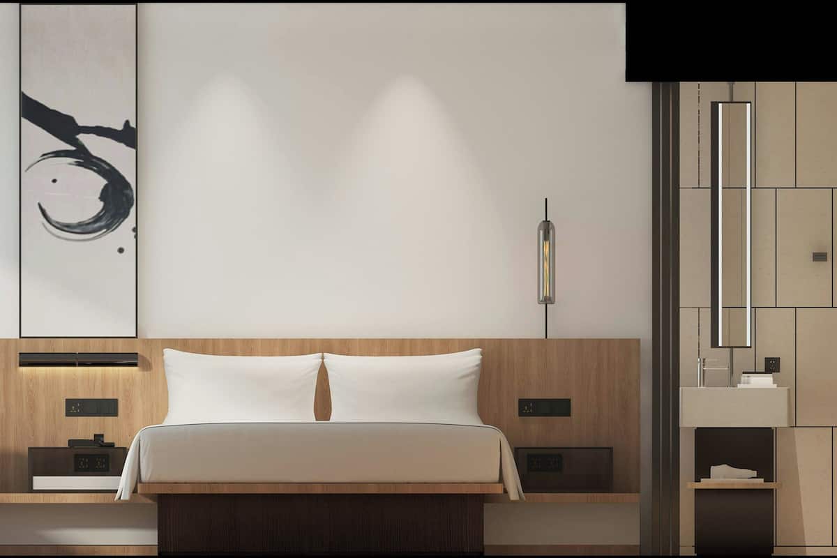 Ein modernes Schlafzimmer mit einem Holz-Kopfteil, einem großen Bett mit weißen Leinen, einer Wandleuchte und minimalistischer Einrichtung.