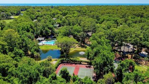 An aerial view of a resort with a swimming pool, tennis courts, and a lake. - Golden Hour Deck Views + Island Fun Await at This Spacious 3BR Retreat (Hilton Head Island)