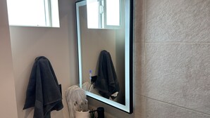 Ein Badezimmer mit Spiegel, Handtuchhalter und Waschbecken.