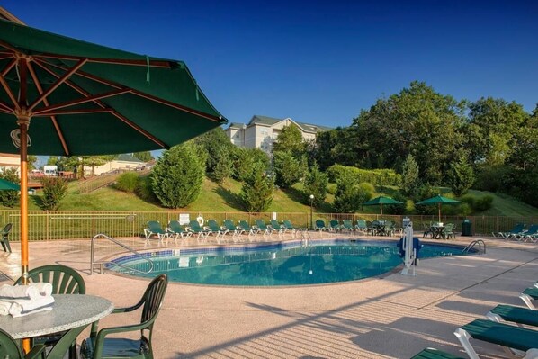 A pool area with lounge chairs, umbrellas, and a clear view of a residential neighborhood. - Scenic Balcony + Full Kitchen in Bright Retreat Near Ozark Trails | 3 Units (Branson)