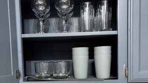 Una cocina con un tostador, un juego de cuchillos y un mueble con varios vasos y tazas.