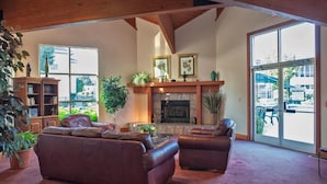 A spacious living room with a fireplace, leather sofas, and large windows offering a view of the outdoors.