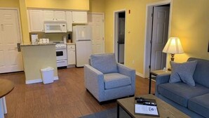 Un espacio habitable compacto con kitchenette, sillones grises, un sofá y una mesa de centro.