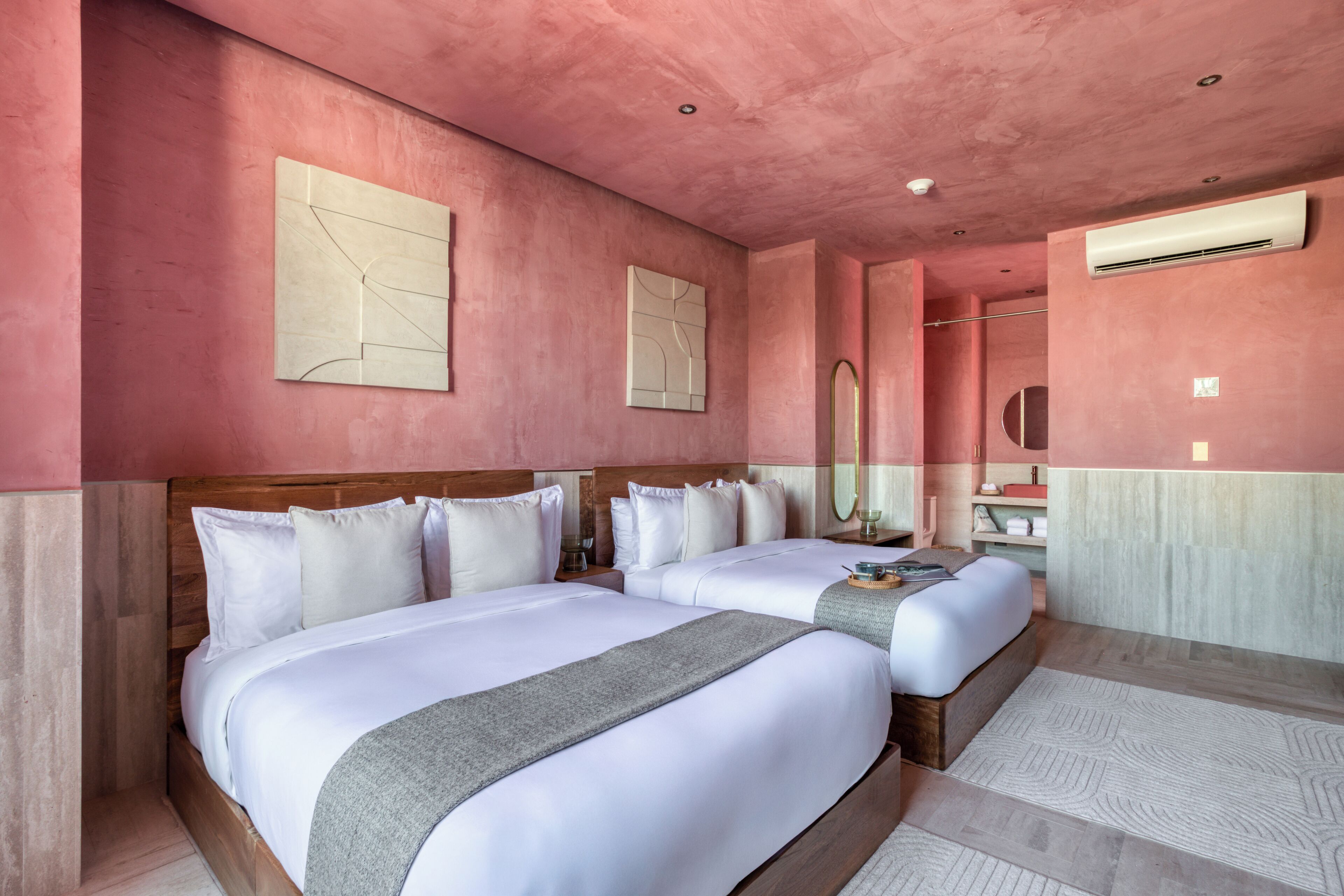 Ein Hotelzimmer mit zwei Betten, einem großen Spiegel und einem hölzernen Kopfteil.