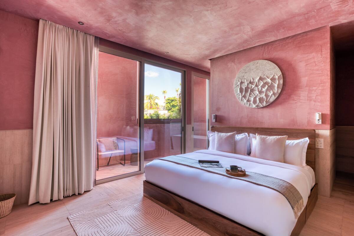 Een slaapkamer met een groot bed, een schuifdeur naar een balkon en een ronde wandversiering.