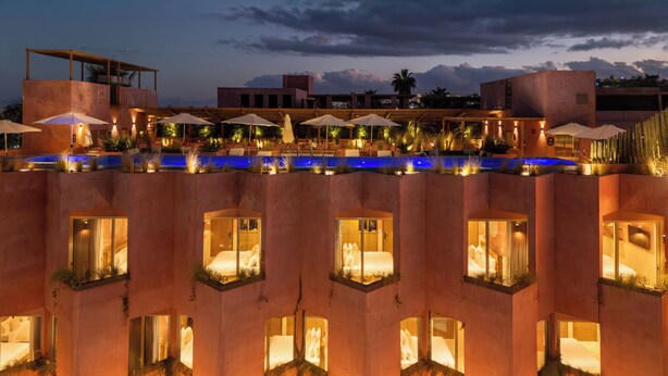 Un hotel con varias habitaciones, balcones, piscina y zonas de estar al aire libre.