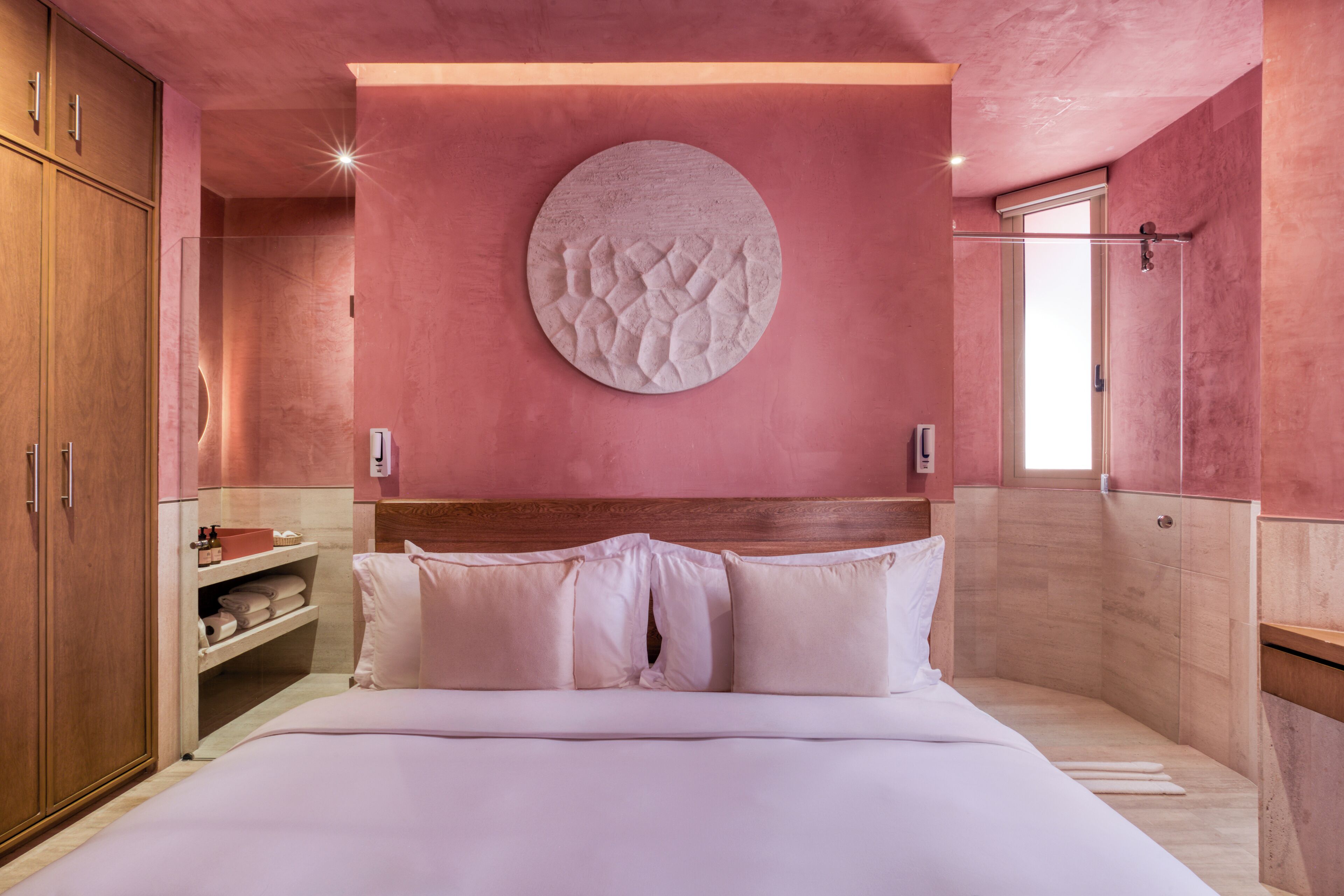 A bedroom with a wooden headboard, a circular wall decoration, and a built-in shelf with towels.